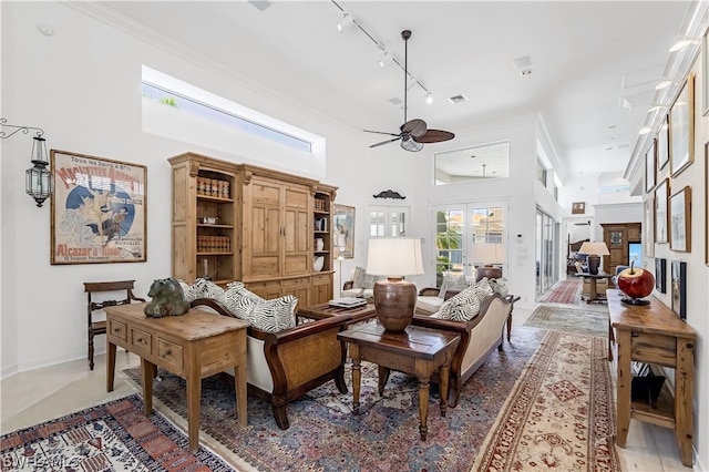 living room with french doors, track lighting, ceiling fan, ornamental molding, and a high ceiling