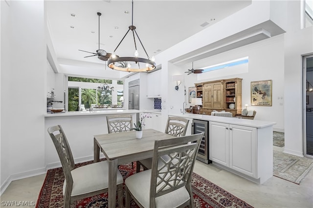 tiled dining room featuring sink, wine cooler, and ceiling fan with notable chandelier