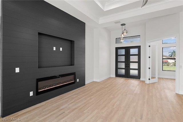 entrance foyer with light hardwood / wood-style flooring, a fireplace, french doors, and ornamental molding