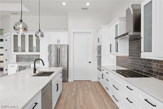 kitchen featuring light hardwood / wood-style floors, tasteful backsplash, wall chimney exhaust hood, and stainless steel appliances