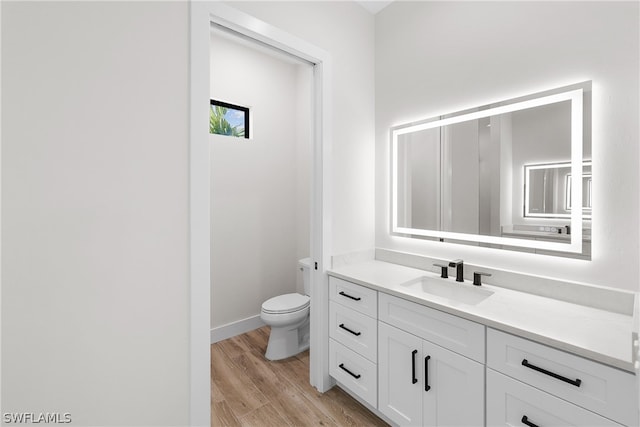 bathroom with toilet, vanity, and hardwood / wood-style floors