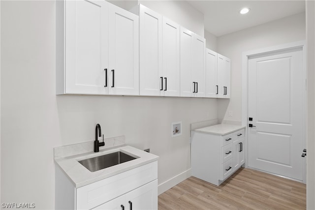 laundry room with washer hookup, light hardwood / wood-style flooring, cabinets, and sink