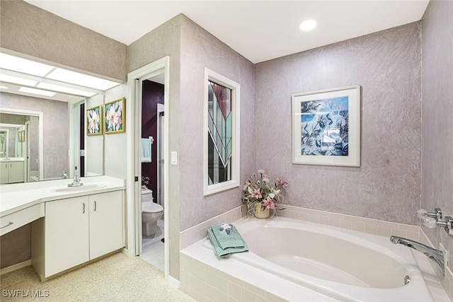 bathroom with vanity, a relaxing tiled tub, and toilet