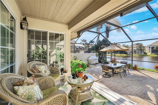 view of patio / terrace with a water view, area for grilling, and glass enclosure