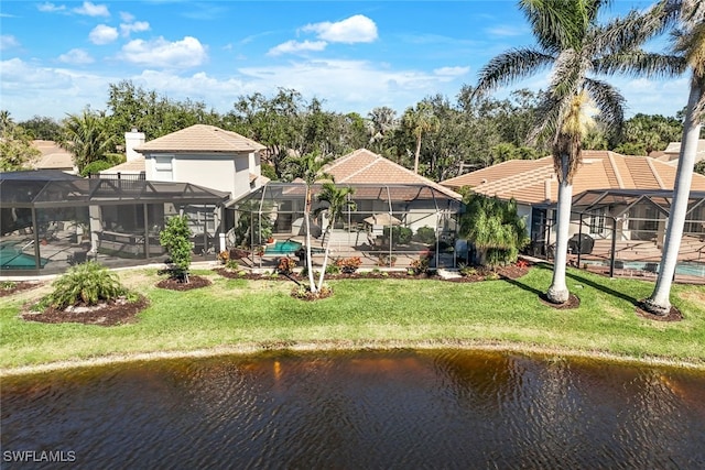 rear view of house with a yard, a lanai, and a water view