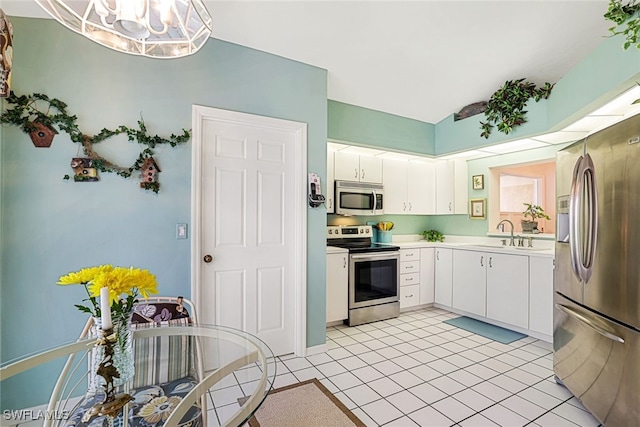 kitchen with light tile patterned flooring, appliances with stainless steel finishes, sink, white cabinets, and a chandelier