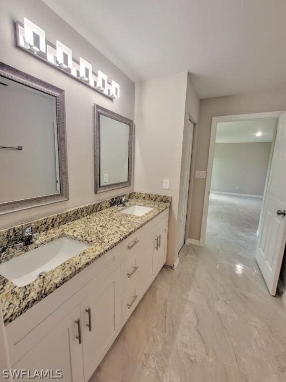 bathroom featuring marble finish floor, a sink, baseboards, and double vanity