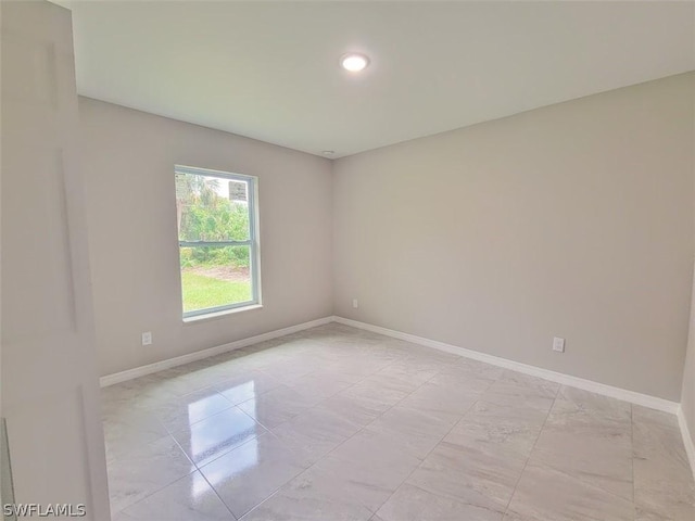 spare room with marble finish floor and baseboards