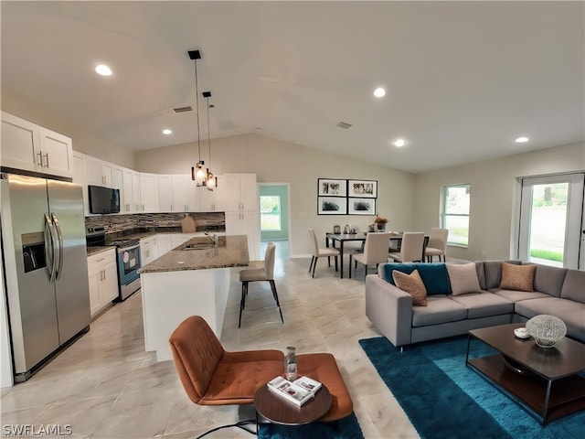 kitchen with a breakfast bar area, a sink, white cabinetry, appliances with stainless steel finishes, and dark stone countertops