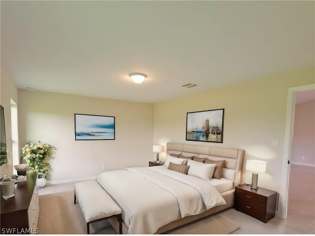 bedroom with baseboards, visible vents, and light colored carpet