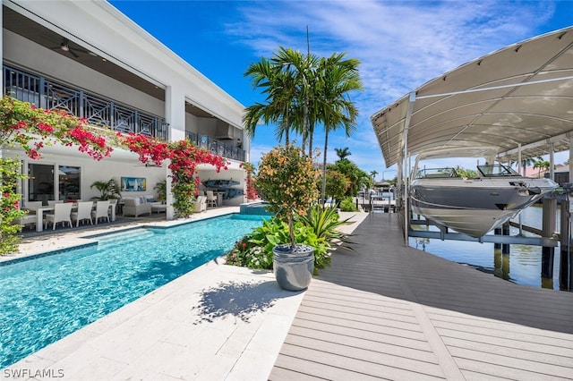 exterior space with a patio, boat lift, outdoor lounge area, a pool with connected hot tub, and a boat dock