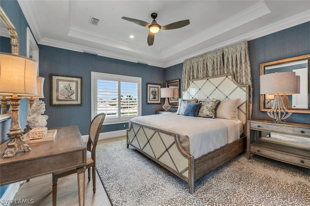 bedroom with ornamental molding, a raised ceiling, visible vents, and wood finished floors