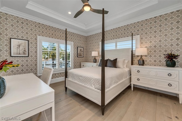 bedroom featuring wallpapered walls, ornamental molding, light wood finished floors, and a tray ceiling