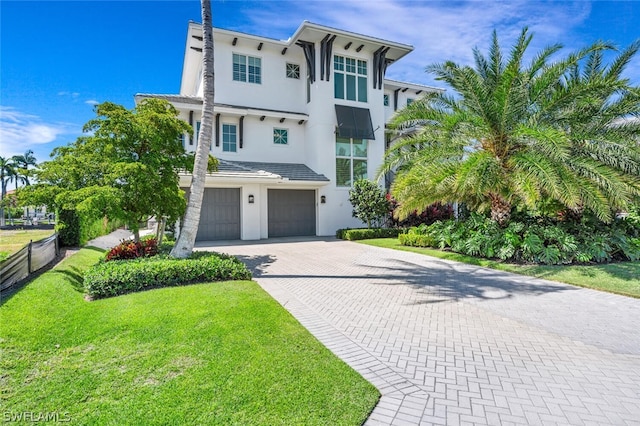 view of front of house with decorative driveway, a front yard, fence, and stucco siding