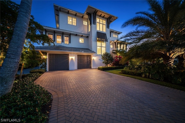 view of front of home featuring a garage, decorative driveway, and stucco siding