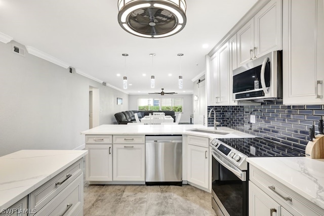 kitchen featuring sink, appliances with stainless steel finishes, decorative light fixtures, light stone counters, and white cabinetry