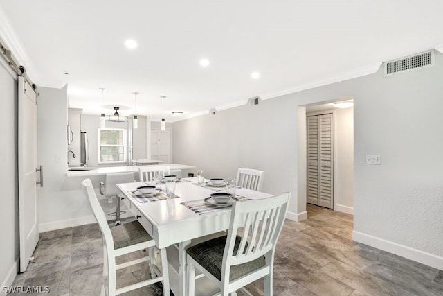 dining space featuring a barn door, ornamental molding, and sink