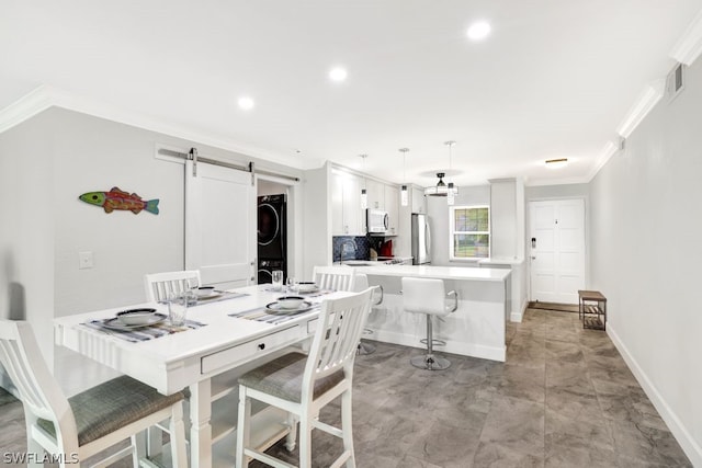 dining space featuring a barn door, stacked washing maching and dryer, and ornamental molding