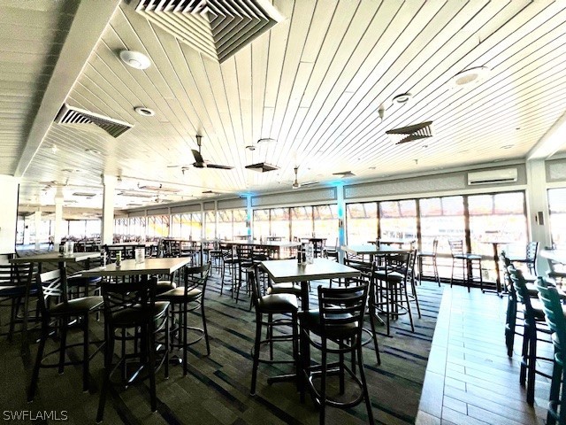 dining area featuring a wall mounted AC, wood ceiling, and ceiling fan