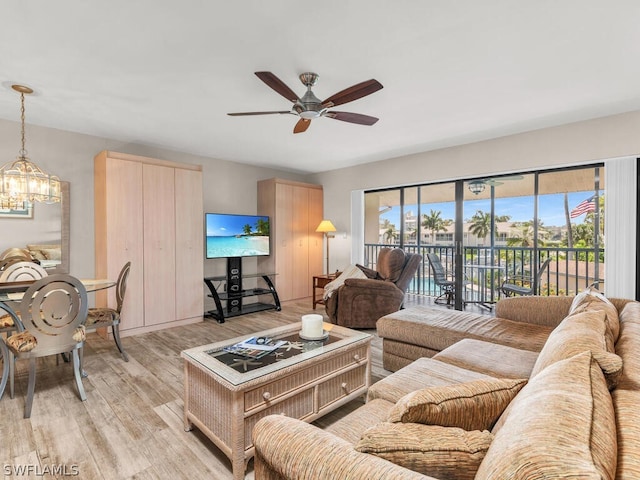 living room with light hardwood / wood-style flooring, a wealth of natural light, and ceiling fan with notable chandelier