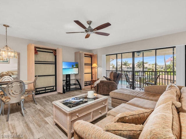 living room featuring ceiling fan with notable chandelier, a wealth of natural light, and light hardwood / wood-style flooring