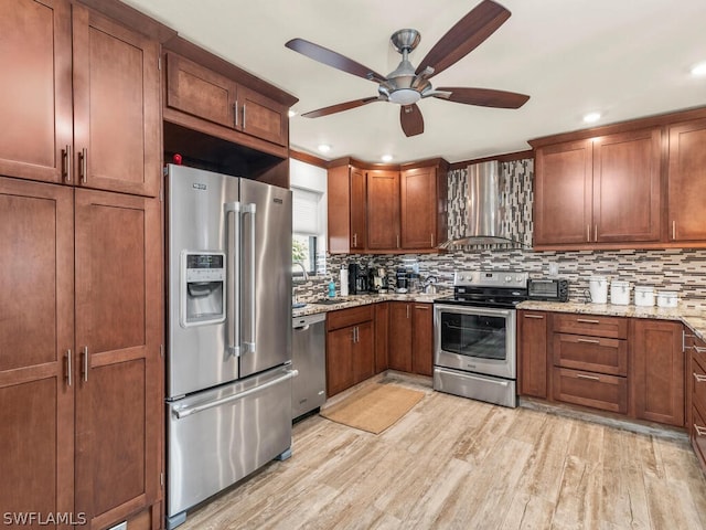 kitchen featuring stainless steel appliances, light stone countertops, ceiling fan, backsplash, and light wood-type flooring