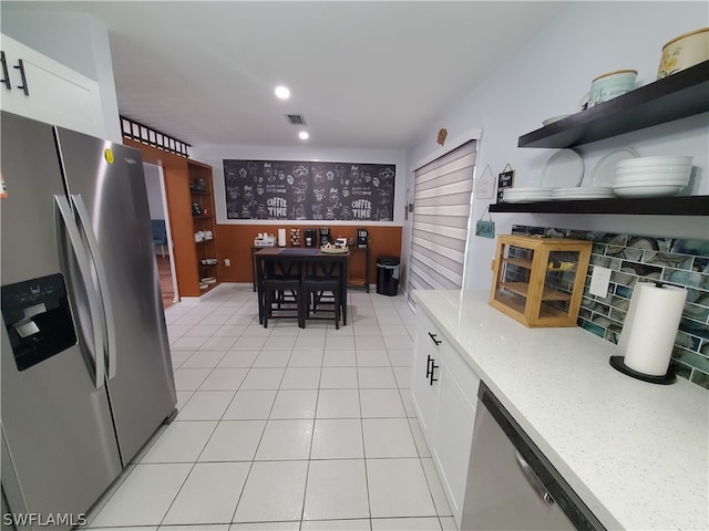 kitchen featuring appliances with stainless steel finishes, white cabinets, light stone counters, backsplash, and light tile patterned floors