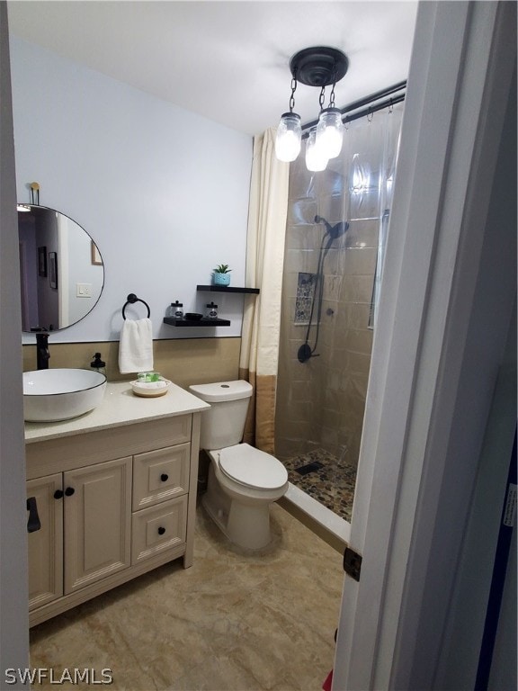 bathroom featuring vanity, a tile shower, tile patterned flooring, and toilet