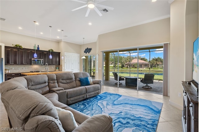 living room with sink, a high ceiling, light tile patterned floors, ceiling fan, and crown molding