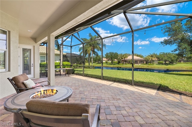 view of patio with a lanai, a water view, and an outdoor fire pit