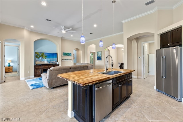 kitchen featuring butcher block counters, sink, a center island with sink, pendant lighting, and stainless steel appliances