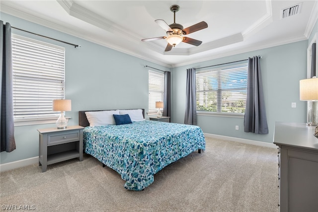 bedroom featuring crown molding, light carpet, ceiling fan, and a tray ceiling