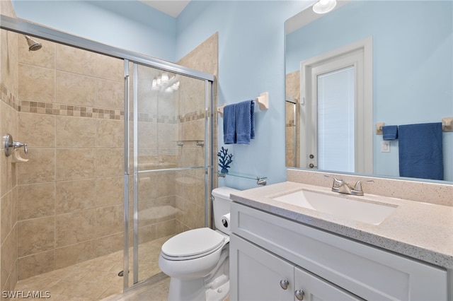 bathroom with a shower with door, vanity, and toilet