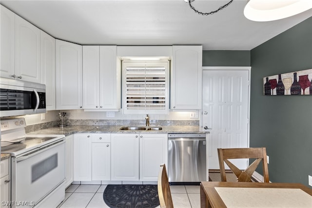 kitchen featuring appliances with stainless steel finishes, sink, white cabinetry, and light tile floors