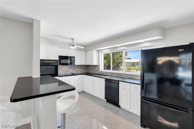 kitchen with a kitchen breakfast bar, kitchen peninsula, white cabinets, and black appliances