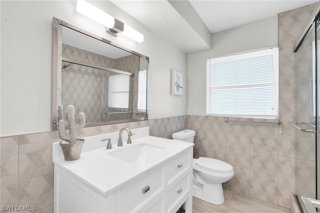 bathroom featuring tile walls, toilet, a shower with shower door, vanity, and tile patterned flooring