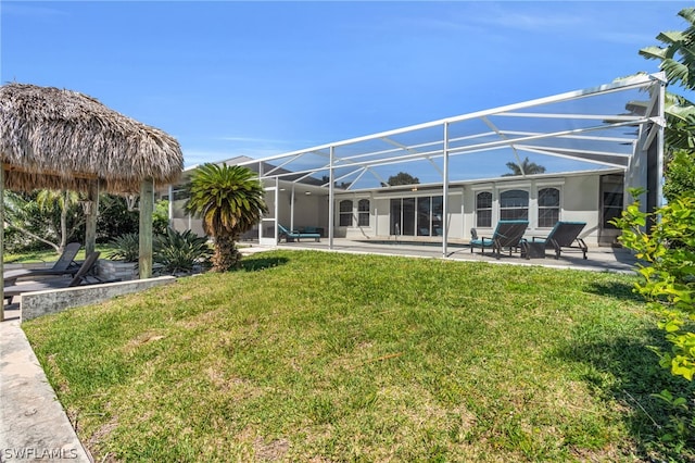 rear view of property featuring a yard, a patio area, and a lanai