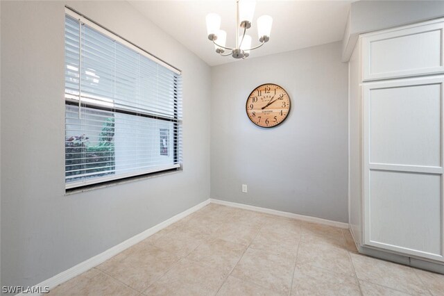 spare room featuring a chandelier and light tile floors