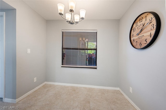 empty room with light tile flooring and a chandelier