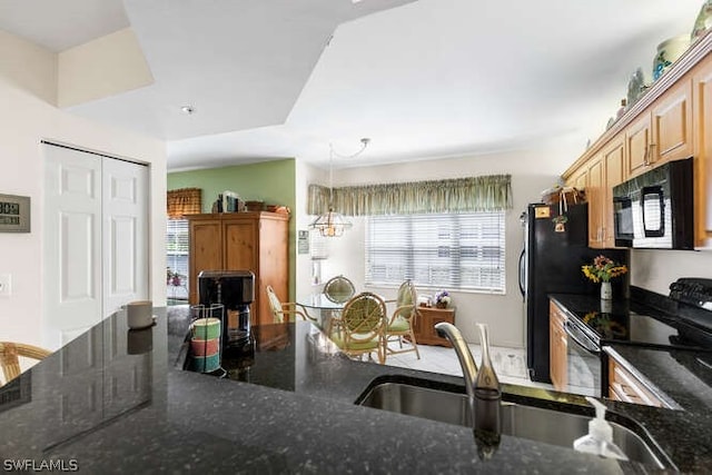 kitchen featuring sink, dark stone countertops, hanging light fixtures, and black appliances