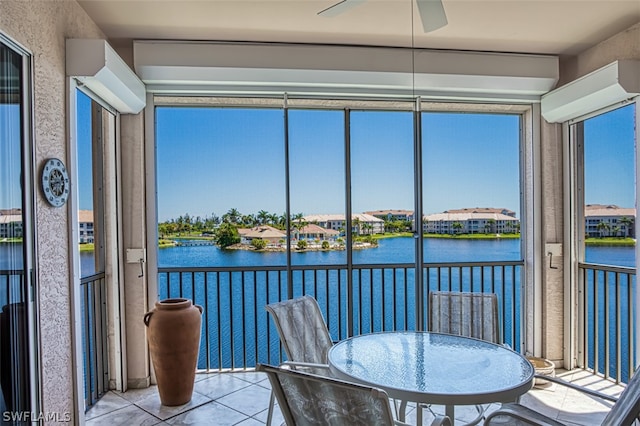 sunroom with ceiling fan and a water view