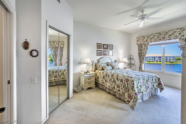 carpeted bedroom with ceiling fan, a closet, and a water view