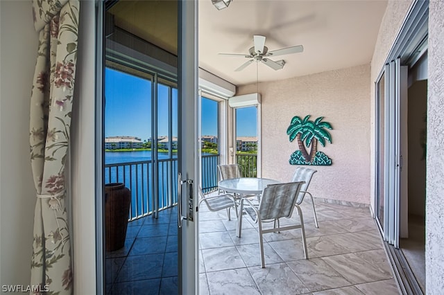 sunroom / solarium with ceiling fan and a water view