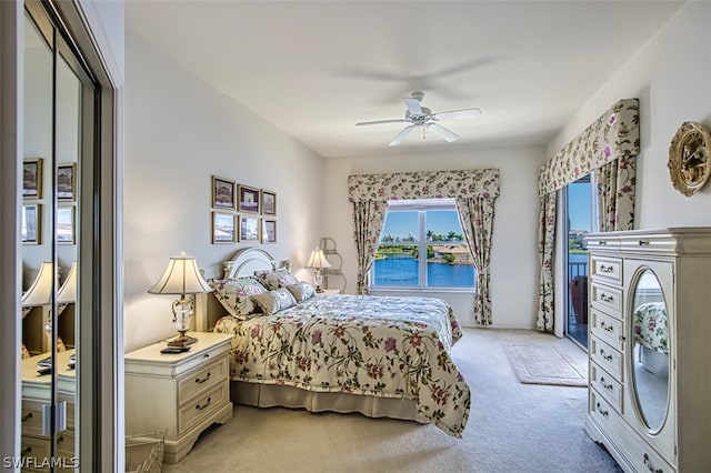 carpeted bedroom featuring ceiling fan and a water view