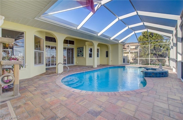 view of swimming pool with glass enclosure, a patio area, and an in ground hot tub