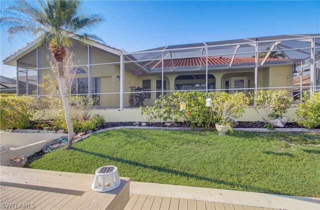 rear view of house featuring a lawn and glass enclosure