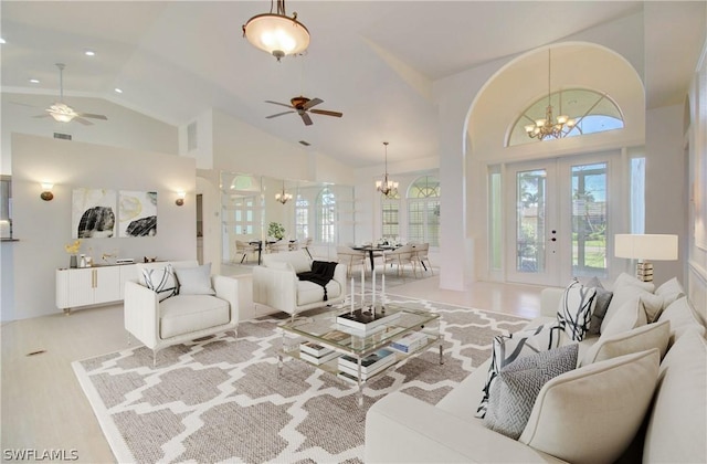 living room featuring french doors, ceiling fan with notable chandelier, and high vaulted ceiling