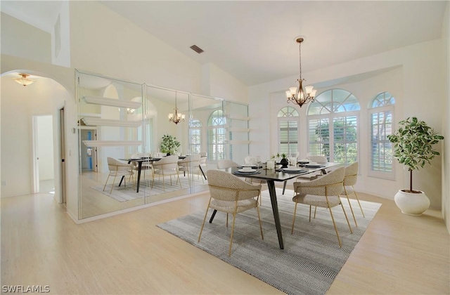 dining area featuring hardwood / wood-style floors, high vaulted ceiling, and a chandelier