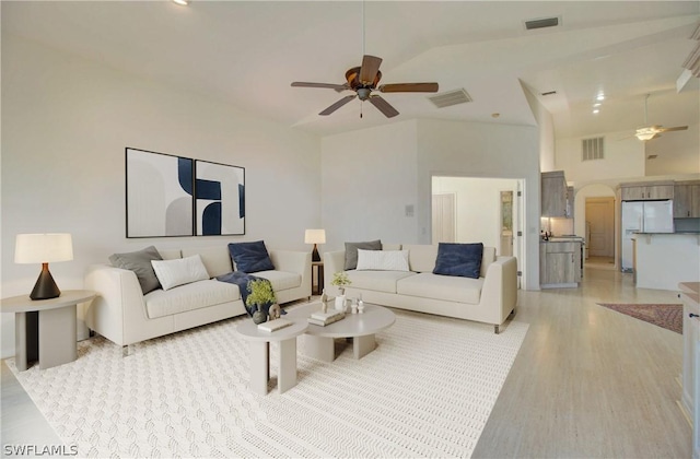 living room featuring ceiling fan, light hardwood / wood-style flooring, and vaulted ceiling