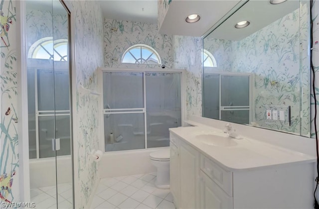 full bathroom with tile patterned floors, vanity, toilet, and bath / shower combo with glass door